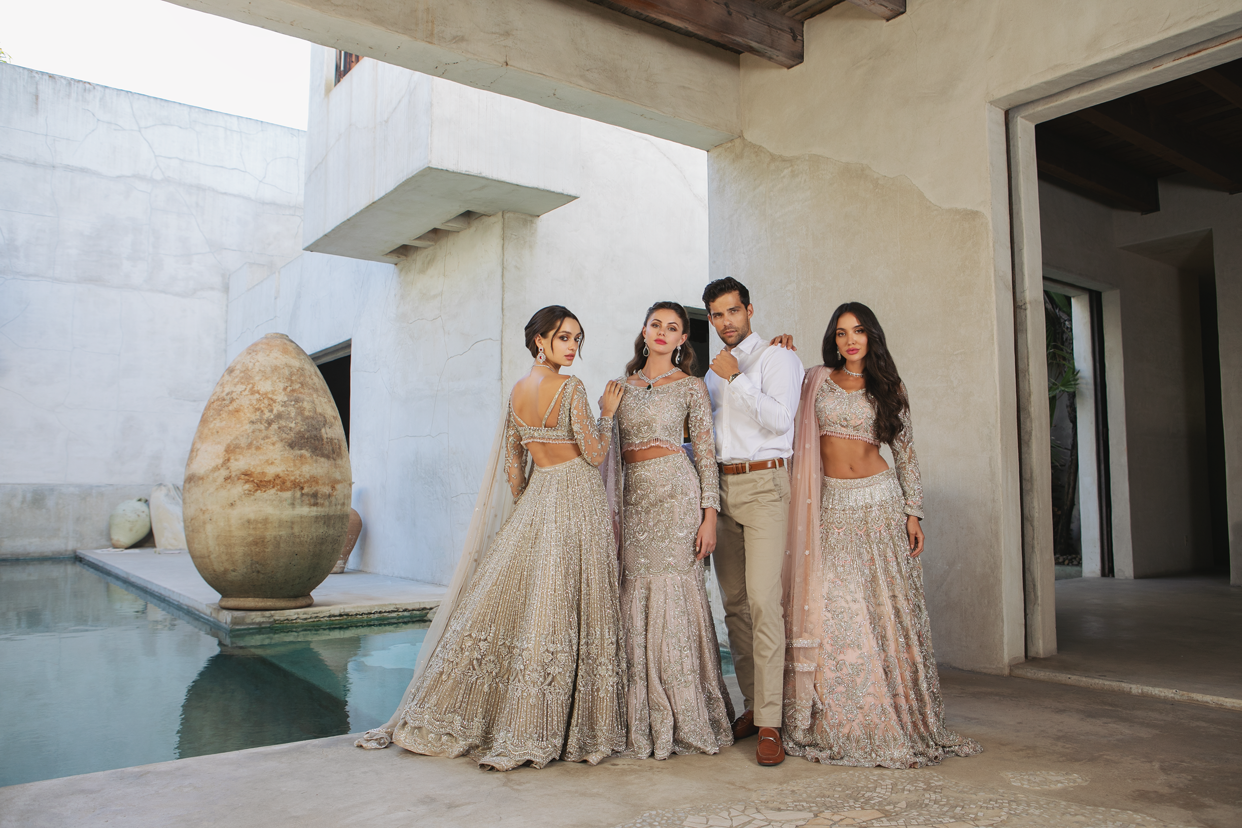 Four people in elegant outfits standing wearing lehenga choli
